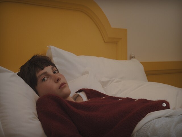 Still from Krapfen by Diego Marcon: a child lying in bed, looking sideways at the camera